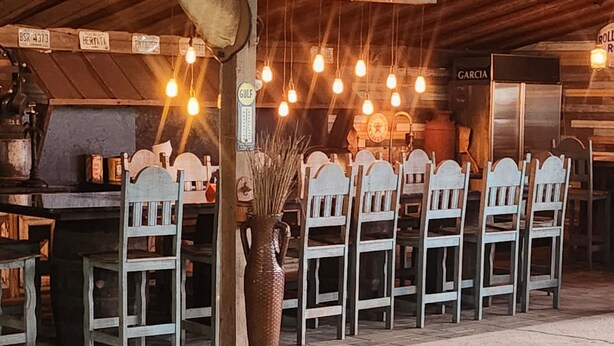Un espace aménagé au bord de la piscine, avec une rangée de chaises blanches et un grand vase.