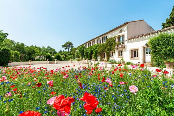 A building with a courtyard filled with flowers, a balcony, and a clear blue sky.