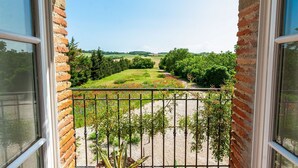 Un balcón con vistas a un paisaje rural, incluyendo campos y árboles.