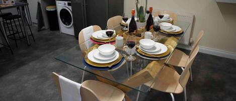 A modern dining area with a glass table set for four, surrounded by chairs.