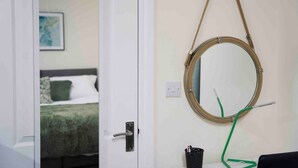 Una stanza con un letto, uno specchio rotondo e una porta.