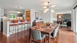 A modern kitchen with a central island, bar stools, and a dining area with a long table and chairs.