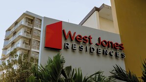 Cartell de West Jones Residences amb un edifici modern al fons.