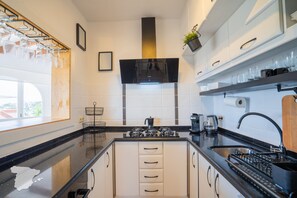 Une cuisine moderne dotée d’un îlot central, de meubles blancs et d’un plan de travail noir.