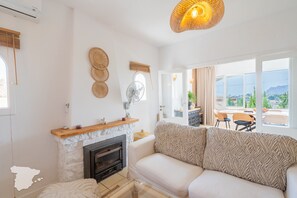 A modern living room with a fireplace, a sofa, and a dining area with a view of the outdoors. - CostaBlancaDreams - Las Mariposas in Benissa (Benissa)
