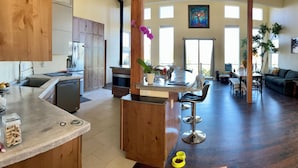 A spacious kitchen with wooden cabinets, a central island, and a dining area with a bar stool.
