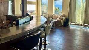 A spacious kitchen with a bar area, large windows, and a ceiling fan.