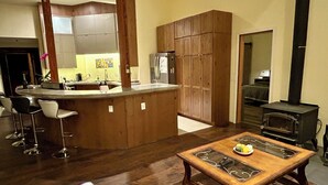 A kitchen with a wooden island, bar stools, a stove, and a dining table with a plate of food.