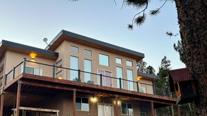 A modern two-story house with a balcony, large windows, and a satellite dish.