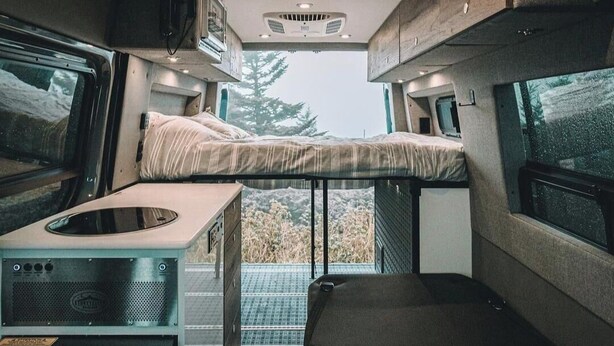 Interior d'una caravana compacta amb dos llits superposats, una cuineta i una petita zona de seients.