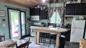 A kitchen with a central island, dark cabinets, a microwave, a stove, and a refrigerator.