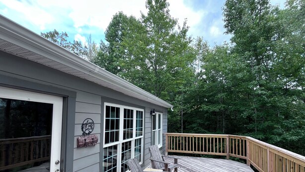 A wooden deck with a railing, a door, and a window with a decorative sign.