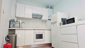 A compact kitchen with white cabinets, a stainless steel sink, a microwave, and a built-in oven. - Modern & comfy oasis in city.  (Anderlecht)