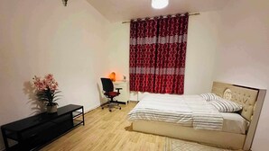A bedroom with a bed, a desk, a chair, a potted plant, and a window with patterned curtains. - Modern & comfy oasis in city.  (Anderlecht)