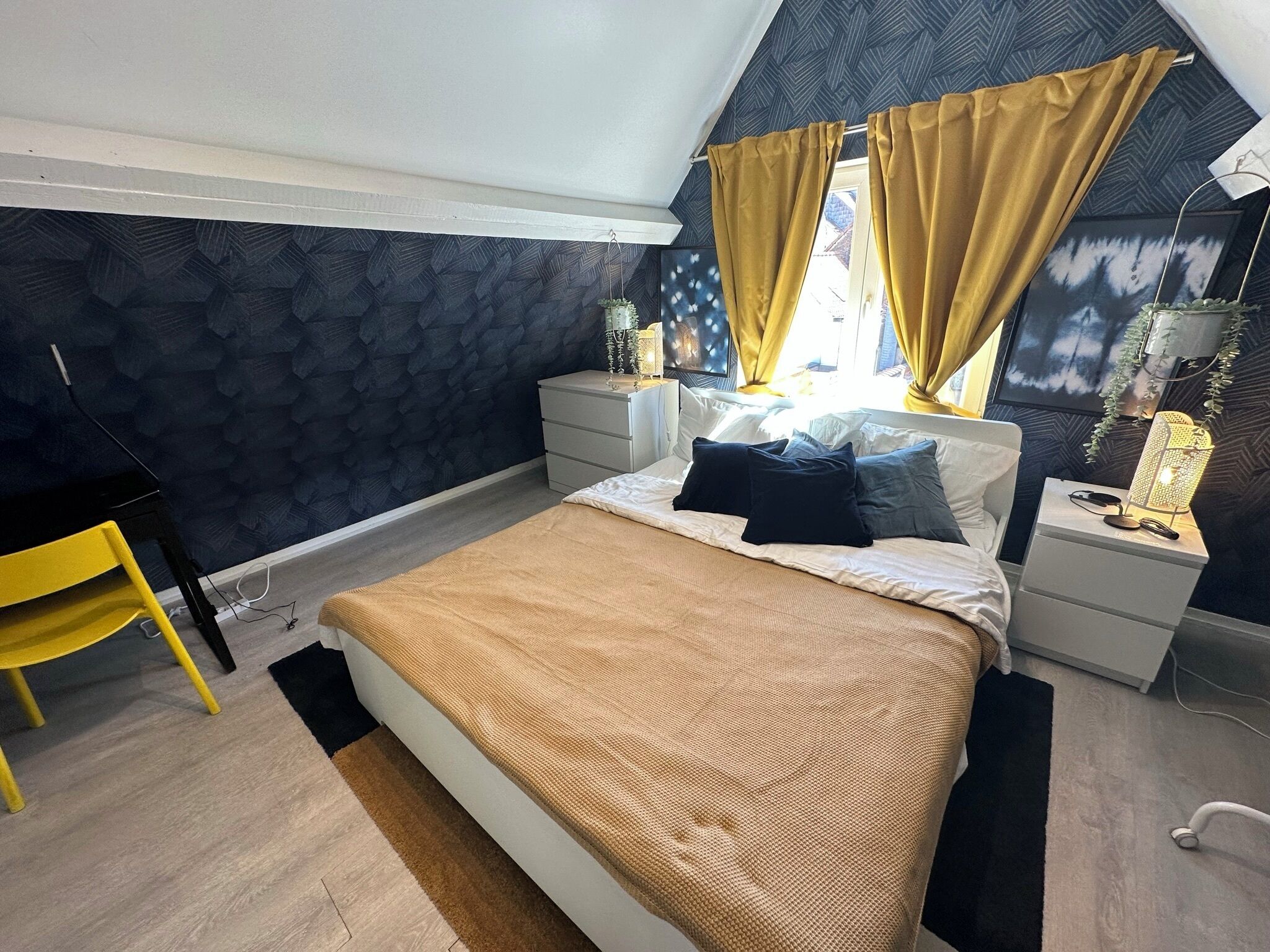 Une chambre à coucher avec un lit, des tables de chevet, un bureau et une chaise.
