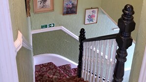 Un escalier avec une rampe blanche, des murs verts et des motifs floraux décorant les murs.