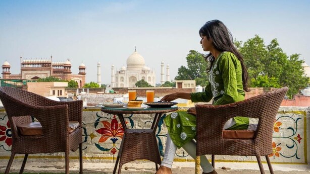 A person seated at a table with a view of the Taj Mahal. - Joey's Hostel Agra (Agra)