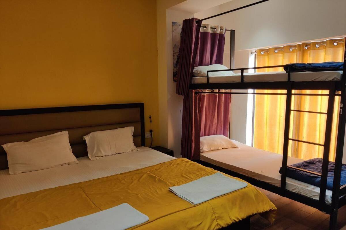 A room with a large bed, a smaller bed, and a bunk bed. There are curtains on the windows, and a window with a view.