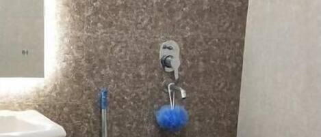 Un baño con pared de mármol, un lavabo, un trapeador, un cubo azul y un inodoro.