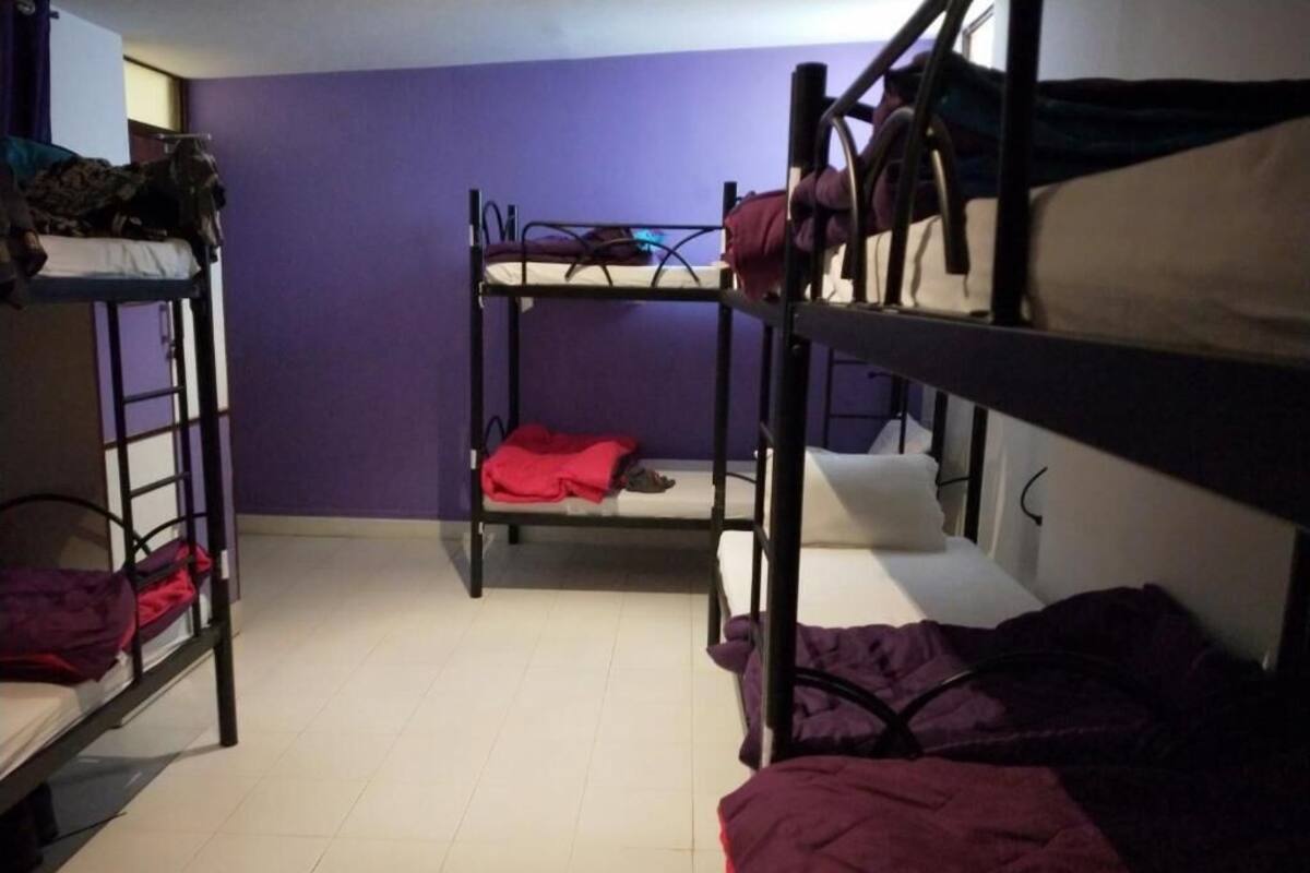 A dormitory room with bunk beds, a purple wall, and a tiled floor.