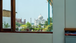 A view of the Taj Mahal through a window with wooden frames and a curtain. - Joey's Hostel Agra (Agra)