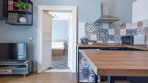 A modern kitchen with a wooden table, a microwave, and a patterned backsplash. - Quiet and cozy in the center, one step away from everything and with a unique view (Catania)