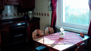 A kitchen with wooden cabinets, a coffee maker, and a window with curtains.