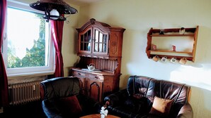 A living room with a wooden cabinet, leather sofa, and a small table with a flower vase.