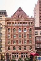 A historic building with a prominent arched entrance, multiple windows, and a brick facade.