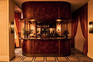 A bar area with a circular marble counter, multiple bottles, and two potted plants. - The Twenty Two New York (New York)
