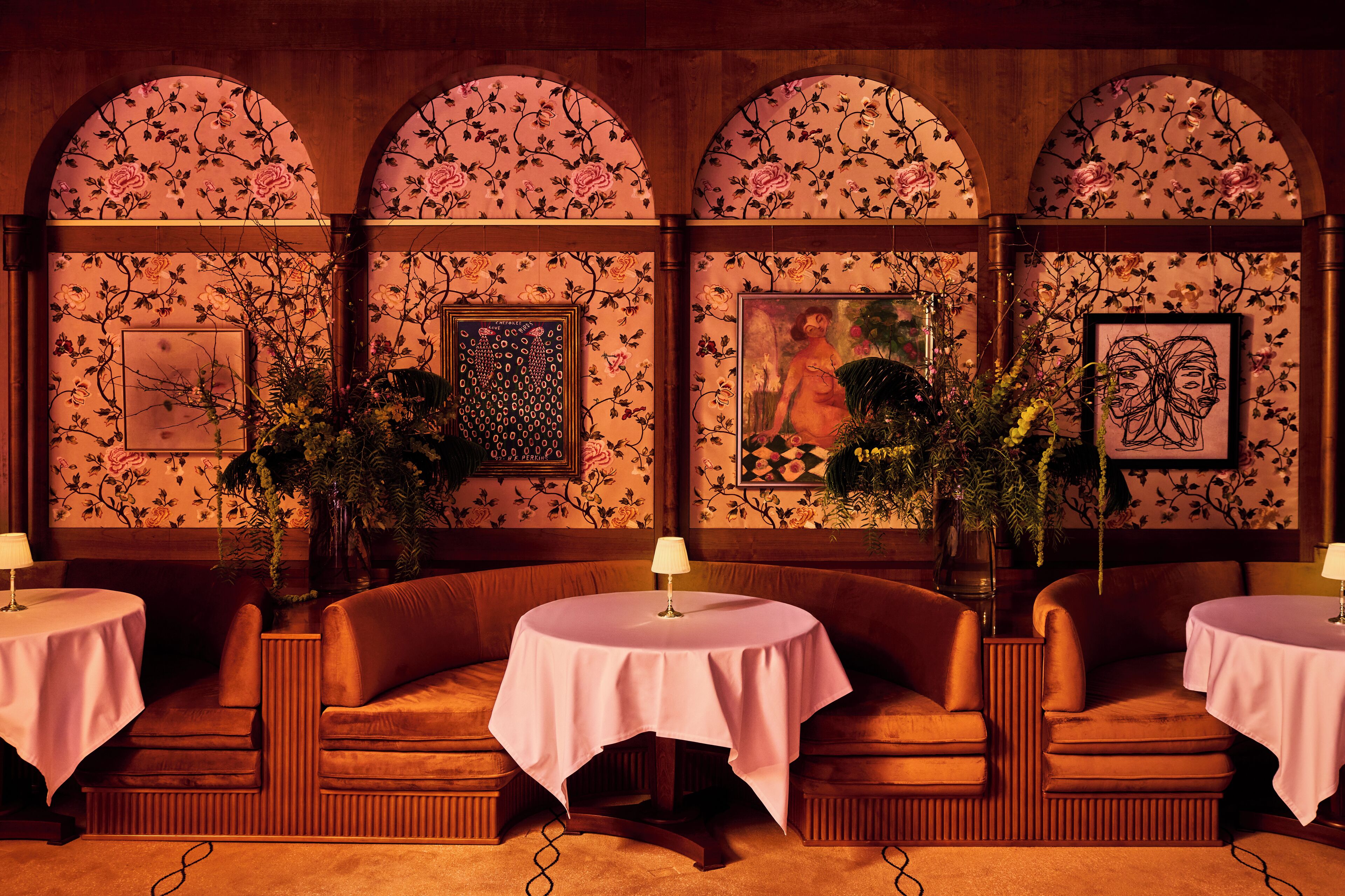 A room with a sofa and a table, both covered with a tablecloth. There are framed pictures on the wall.