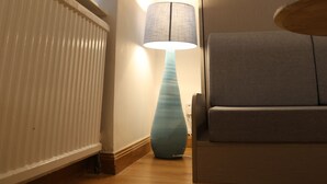 Ein Zimmer mit Heizkörper, Lampe und einer Couch.