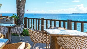 An outdoor seating area with wicker furniture and a view of the sea.