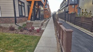 Een woonstraat met moderne huizen, een voetpad en een houten hek.