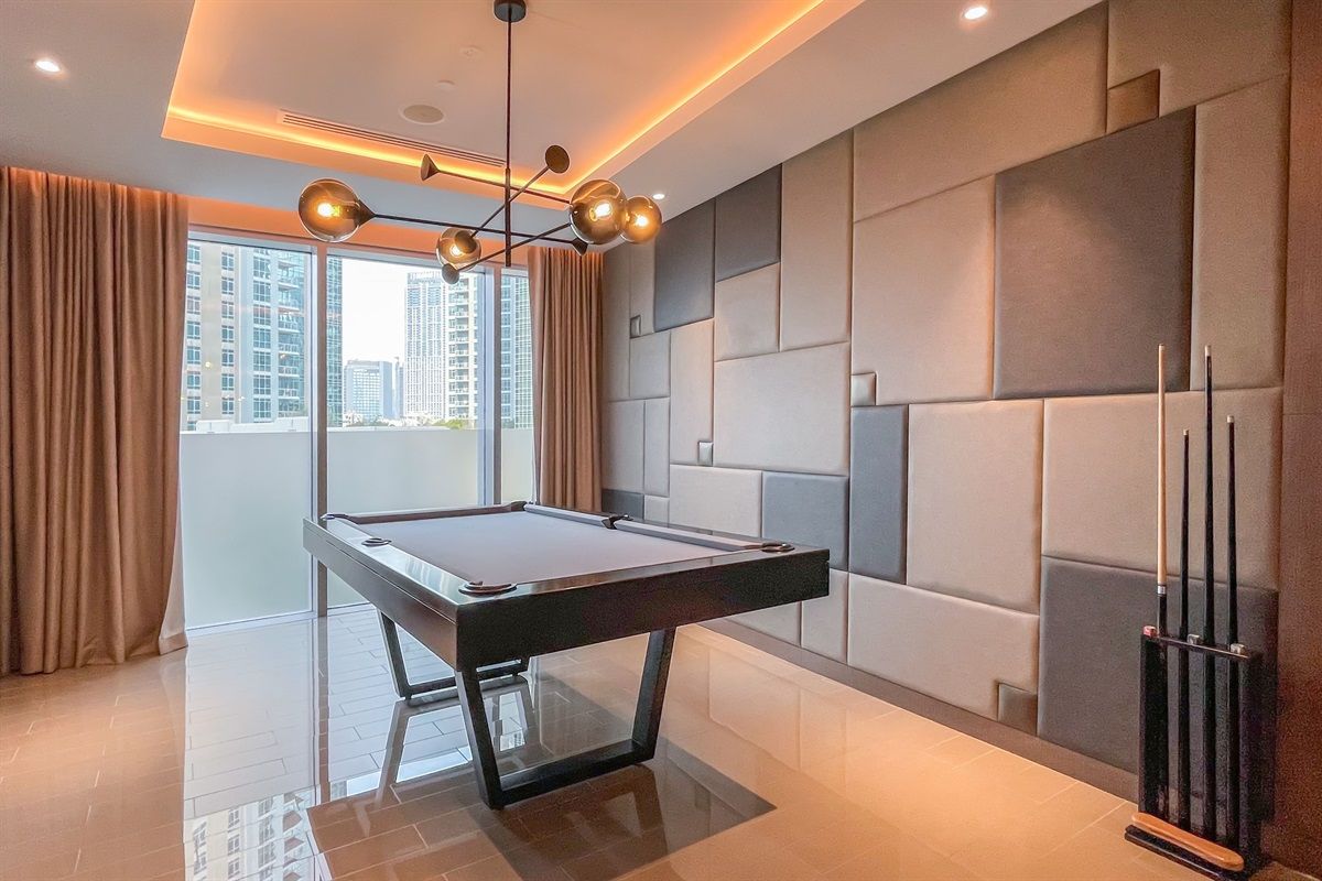 Une pièce moderne équipée d’une table de billard, d’un luminaire au plafond et offrant une vue sur la ville.