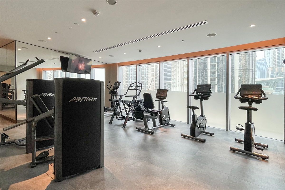 Une salle de sport équipée de machines de cardio, de matériel de musculation et d’un écran de télévision.