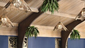 A poolside area with wooden chairs and hanging wicker lamps.