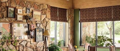 A rustic interior with wooden furniture, stone walls, and large windows.