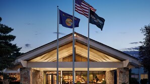 A hotel with a stone facade, a covered outdoor seating area, and two flags.