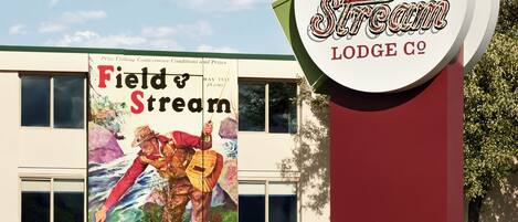 Un bâtiment portant une enseigne indiquant « Field & Stream Lodge Co. », une entreprise fondée en 1871, et orné d’une fresque représentant une scène de pêche.