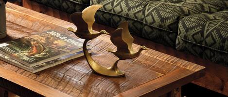 Une table basse en bois, sur laquelle sont posés un livre et des sculptures d’oiseaux décoratives.