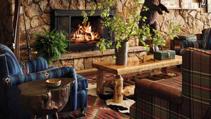 A cozy living room with a stone fireplace, mounted animal heads, and a variety of seating options. - Field & Stream Lodge Bozeman (Bozeman)