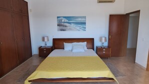 A bedroom with a bed, nightstands, a wooden wardrobe, a painting on the wall, and a door. - Carpe Diem (faro)