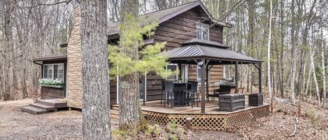 A cabin with a deck, outdoor seating, and a small porch.