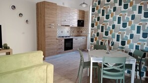 Una cocina moderna con armarios de madera y salpicadero de azulejos. En primer plano, una mesa de comedor con sillas y un sofá amarillo.