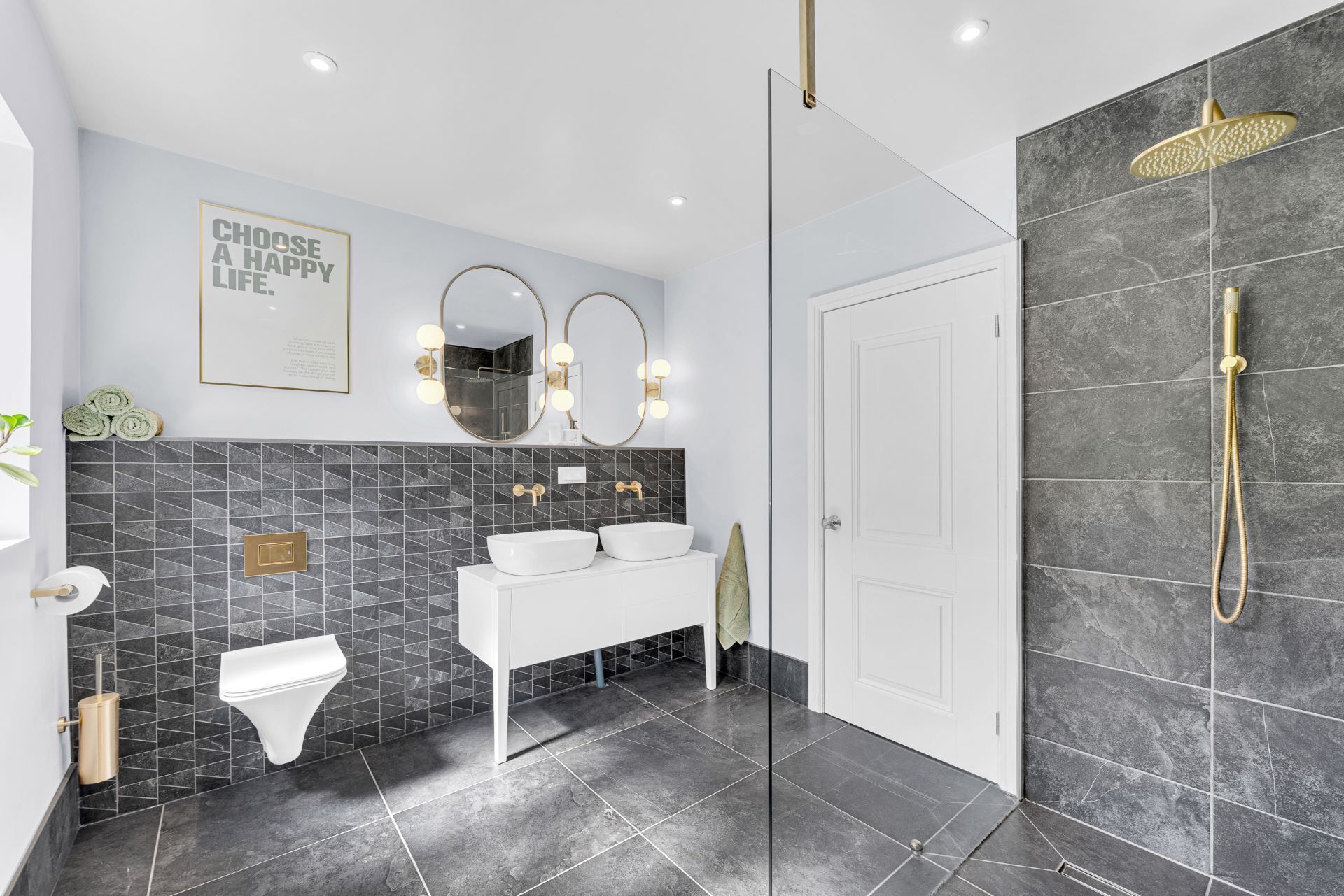 Une salle de bain moderne avec un grand miroir, deux lavabos, des toilettes et un espace douche.