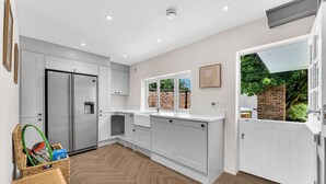Een moderne keuken met witte kasten, een roestvrijstalen koelkast en een visgraatparketvloer.