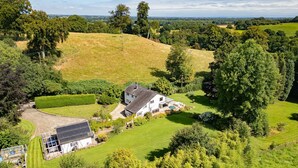 Een groot huis met een ruim gazon, een zonnepaneelinstallatie en een verzorgde tuin.