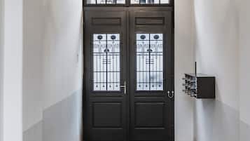 A hallway with a dark double door, a patterned carpet, and a wall-mounted light fixture.