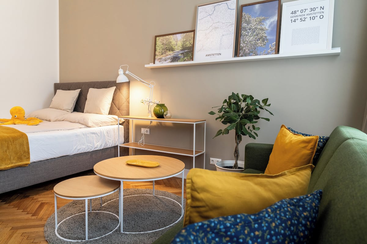 A modern bedroom with a bed, bedside table, lamp, and a small round table.